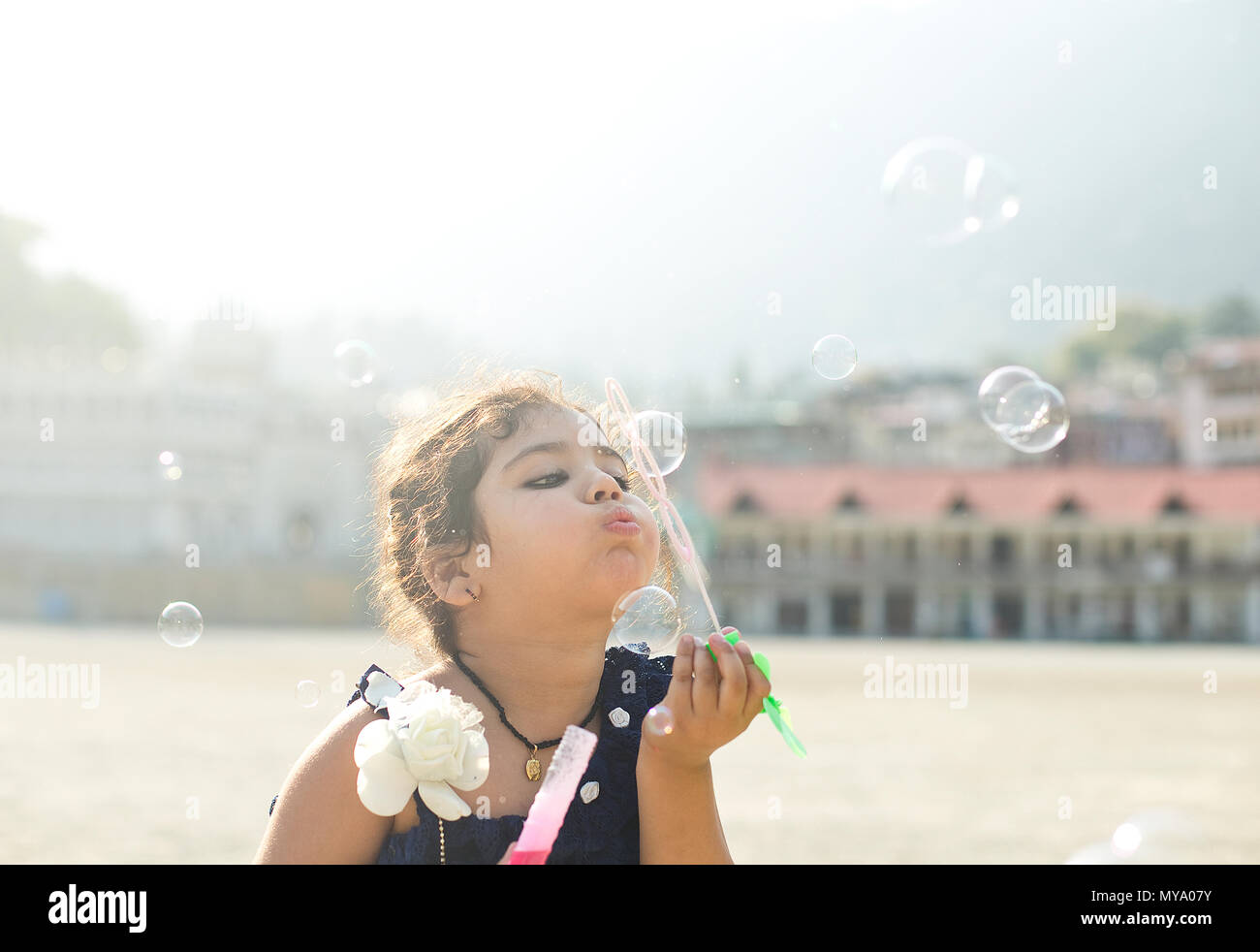 Cute little girl blowing soap bubbles en été Banque D'Images