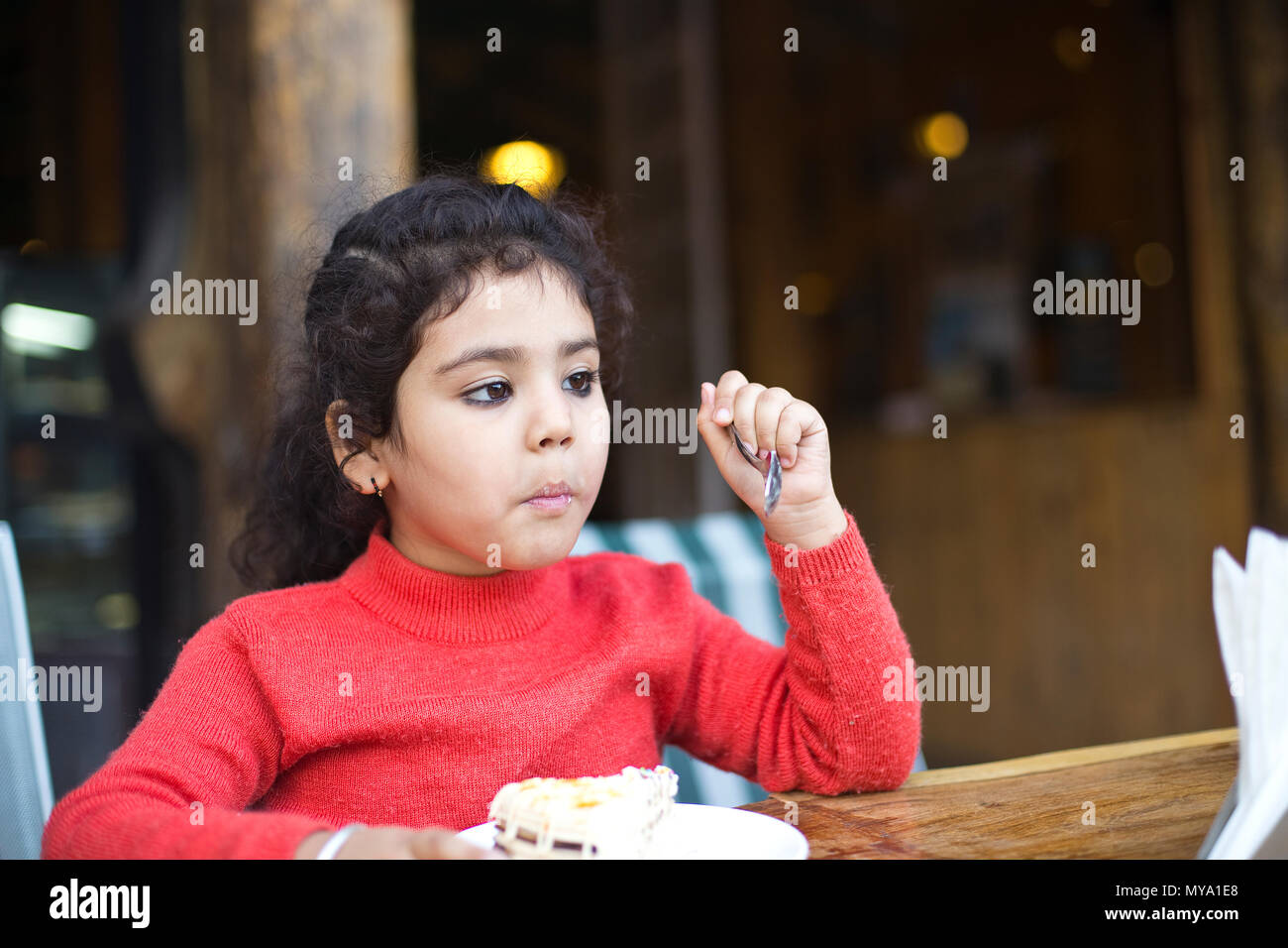 Little girl eating tranche de gâteau au restaurant Banque D'Images