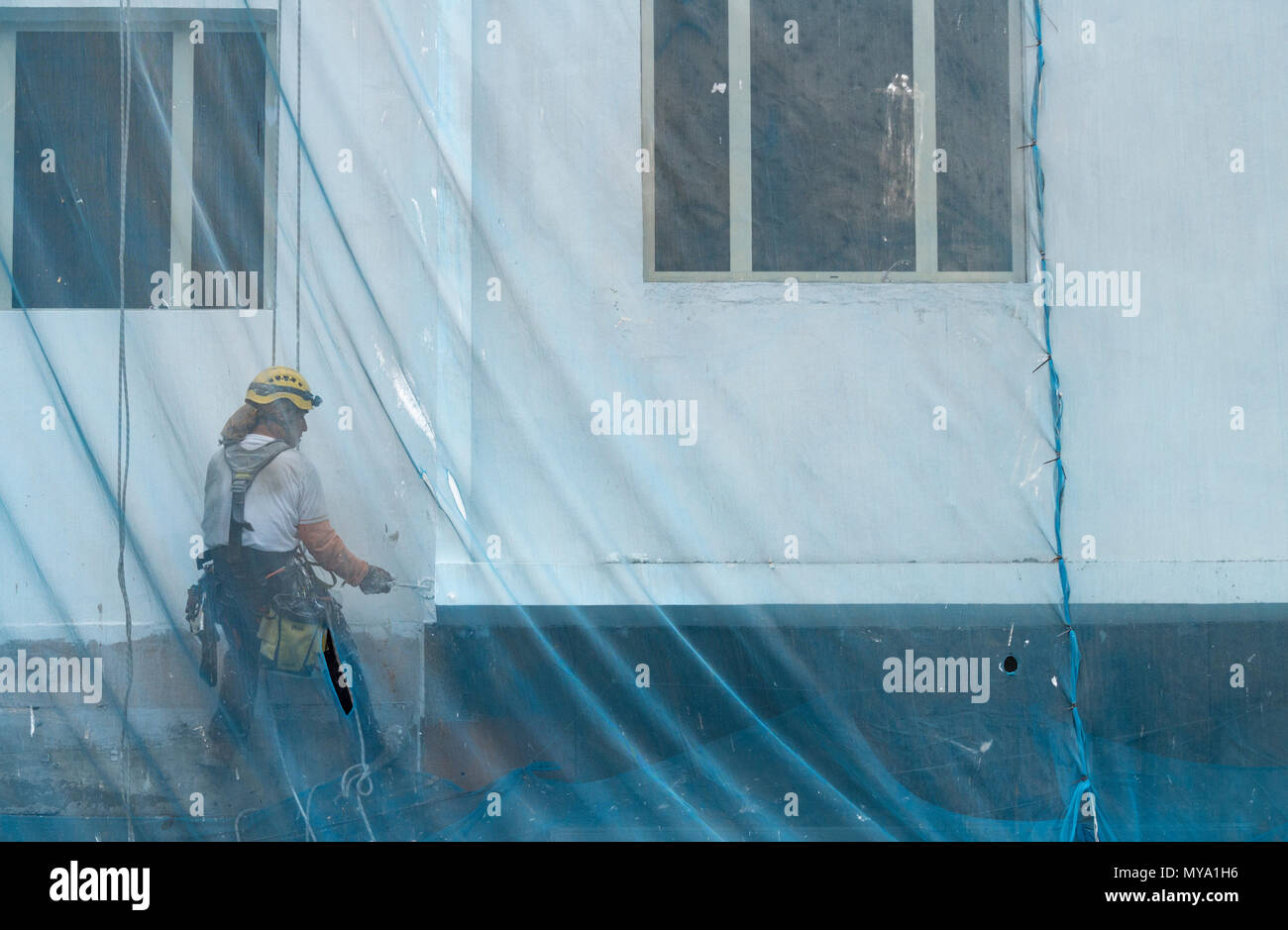 Ouvriers ascending grand bloc d'appartement en Espagne comme il peint avec rouleau. Banque D'Images
