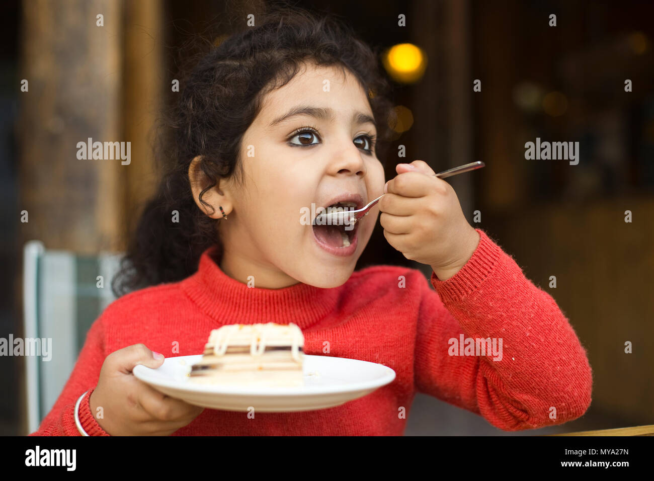 Little girl eating tranche de gâteau au restaurant Banque D'Images