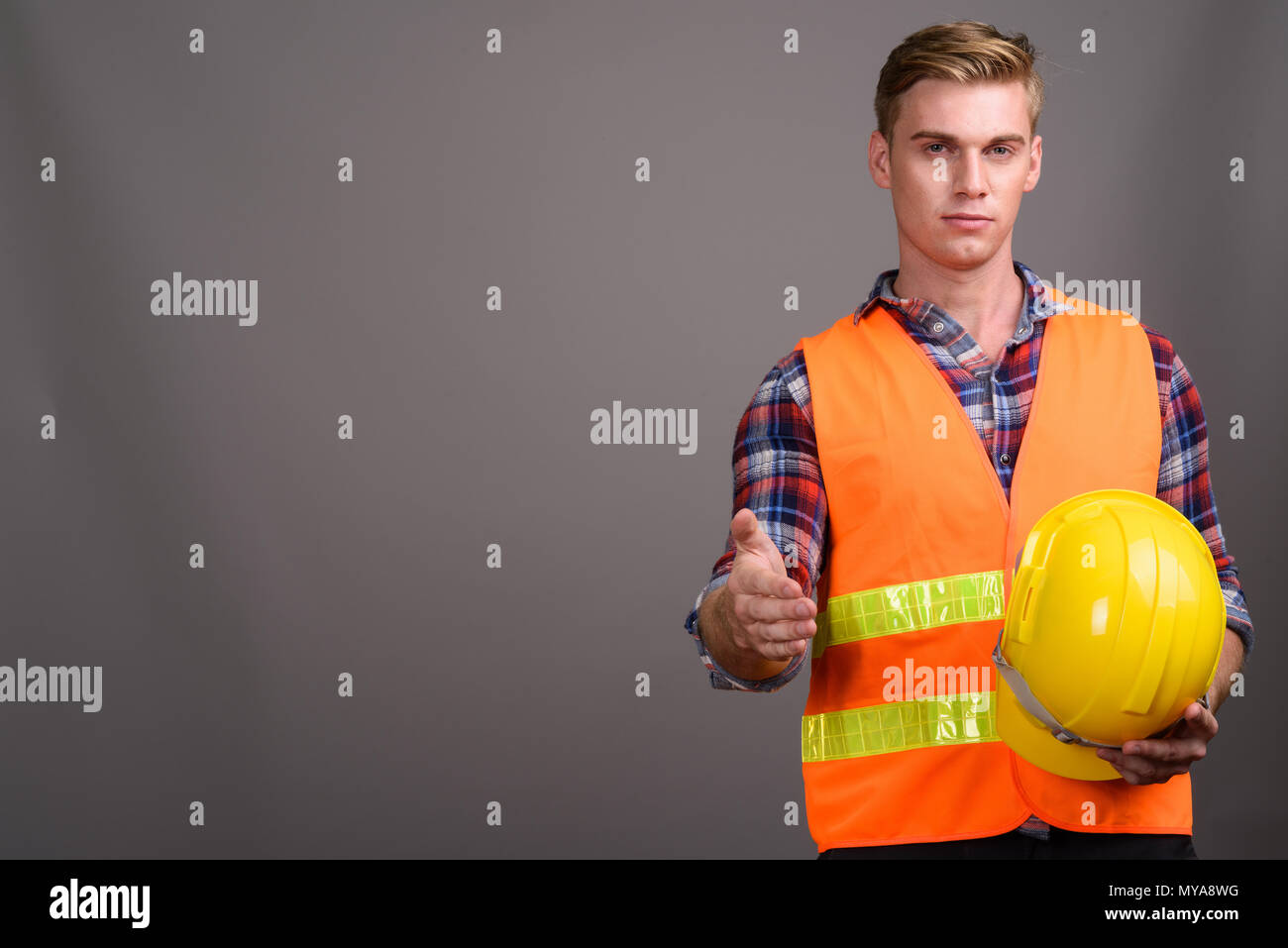 Bel homme jeune travailleur de la construction avec des cheveux blonds contre g Banque D'Images