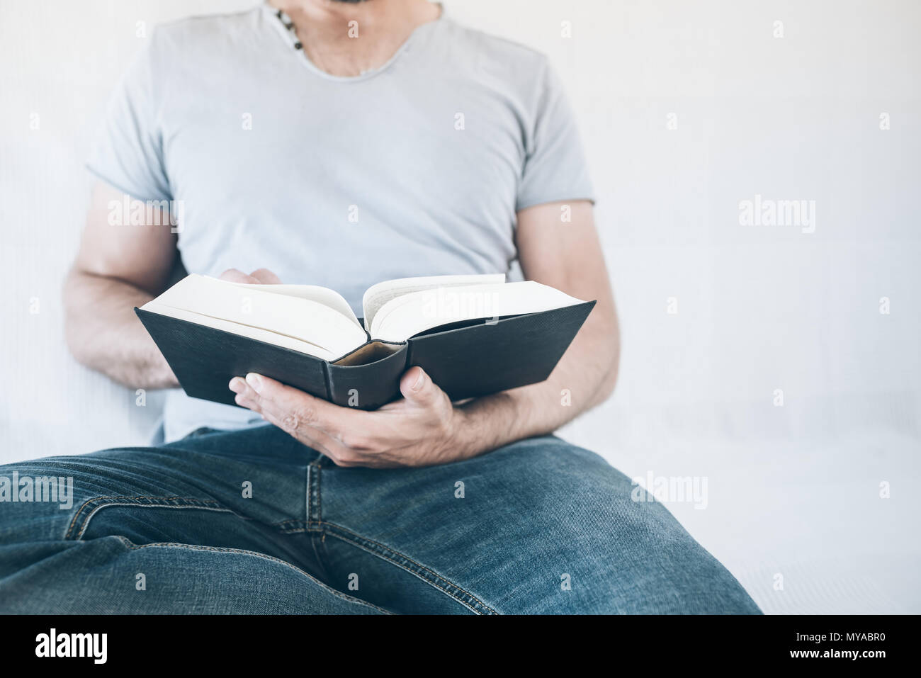 Close-up of man relaxing on sofa reading a book Banque D'Images