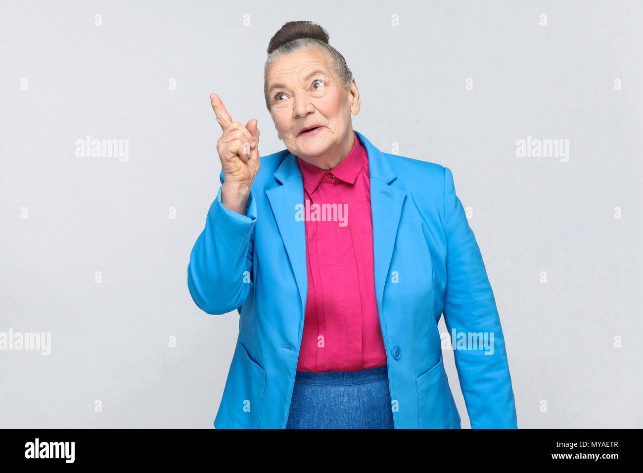 De grand-mère avec nouvelle idée. L'émotion et les sentiments de belle-mère expressive avec costume bleu clair et rose shirt debout avec recueillies bun gr Banque D'Images
