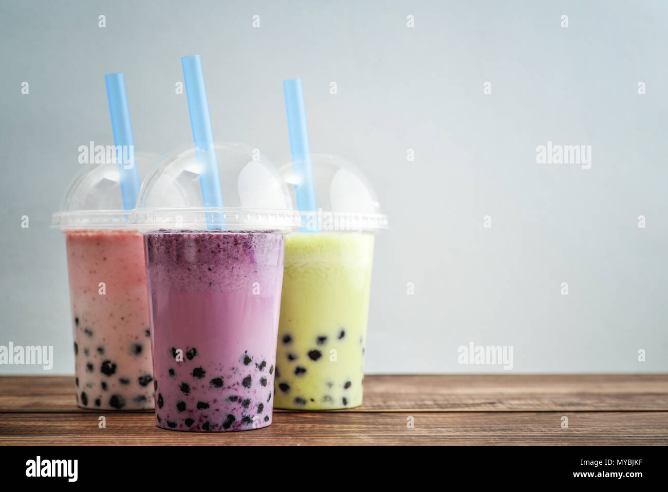 Divers bubble tea dans un verre en plastique tasses avec paille sur fond bleu. Boissons à emporter concept. Banque D'Images