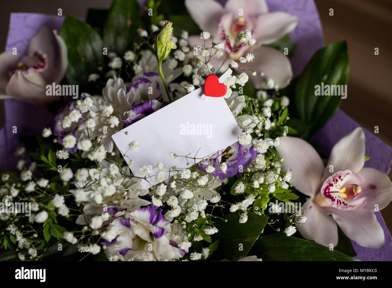 Carte de voeux blanche avec des fleurs blanches bouquet et petit rouge coeur .Vue de dessus la maquette..la maquette de marque élégante pour afficher vos oeuvres.orchidées et lisianthuses. Journée spéciale, un événement, un invatation. Banque D'Images
