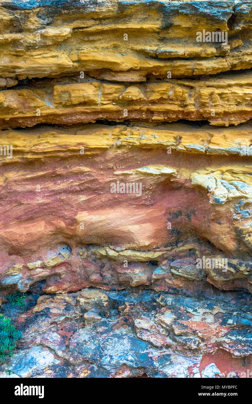 D'une texture colorée des sédiments rocheux avec différentes couches de matériel sur la plage de Nazaré, Portugal. Banque D'Images