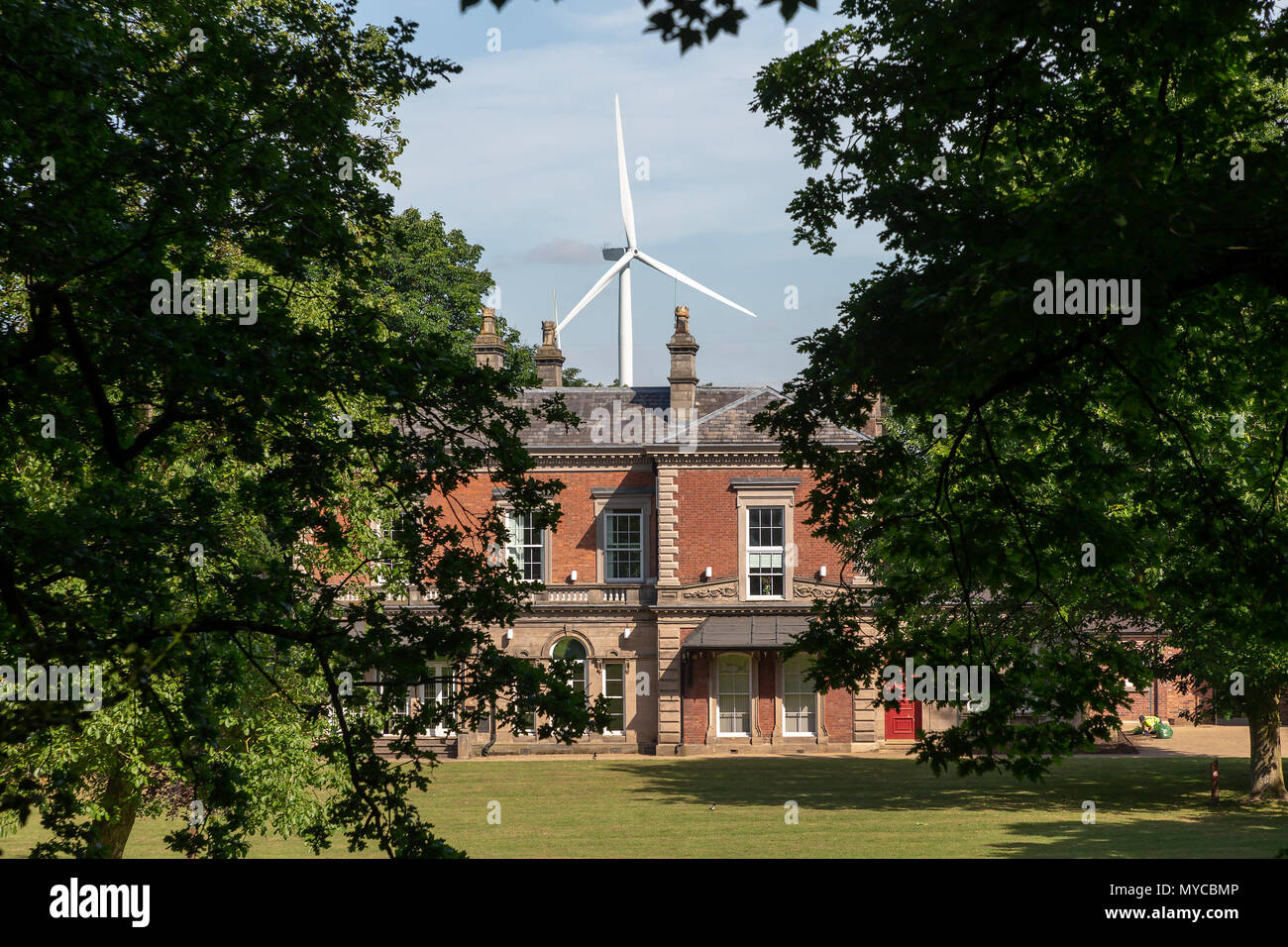 06 juin 2018 - moderne contrastant, éolienne individuelle, est vu s'élevant au-dessus d'un immeuble historique dans le parc du château, Frodsham, Cheshire, England, UK Banque D'Images