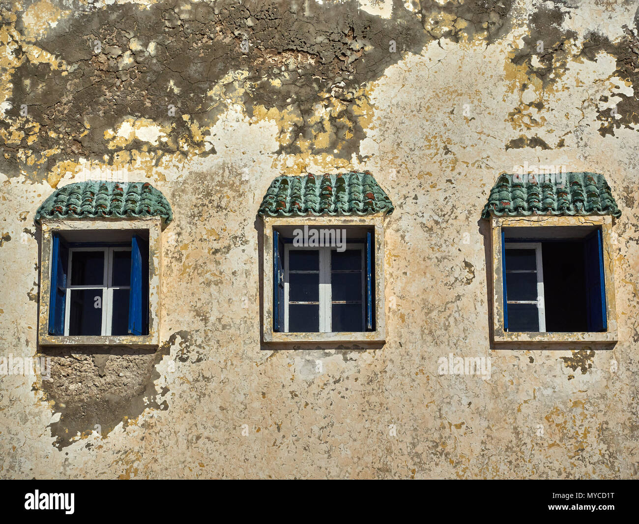 Vintage trois fenêtres avec cadres en bois blanc sur le mur d'une maison ancienne, avec de l'eau et la moisissure, sur les fenêtres de l'écran avec des tuiles vertes. Banque D'Images