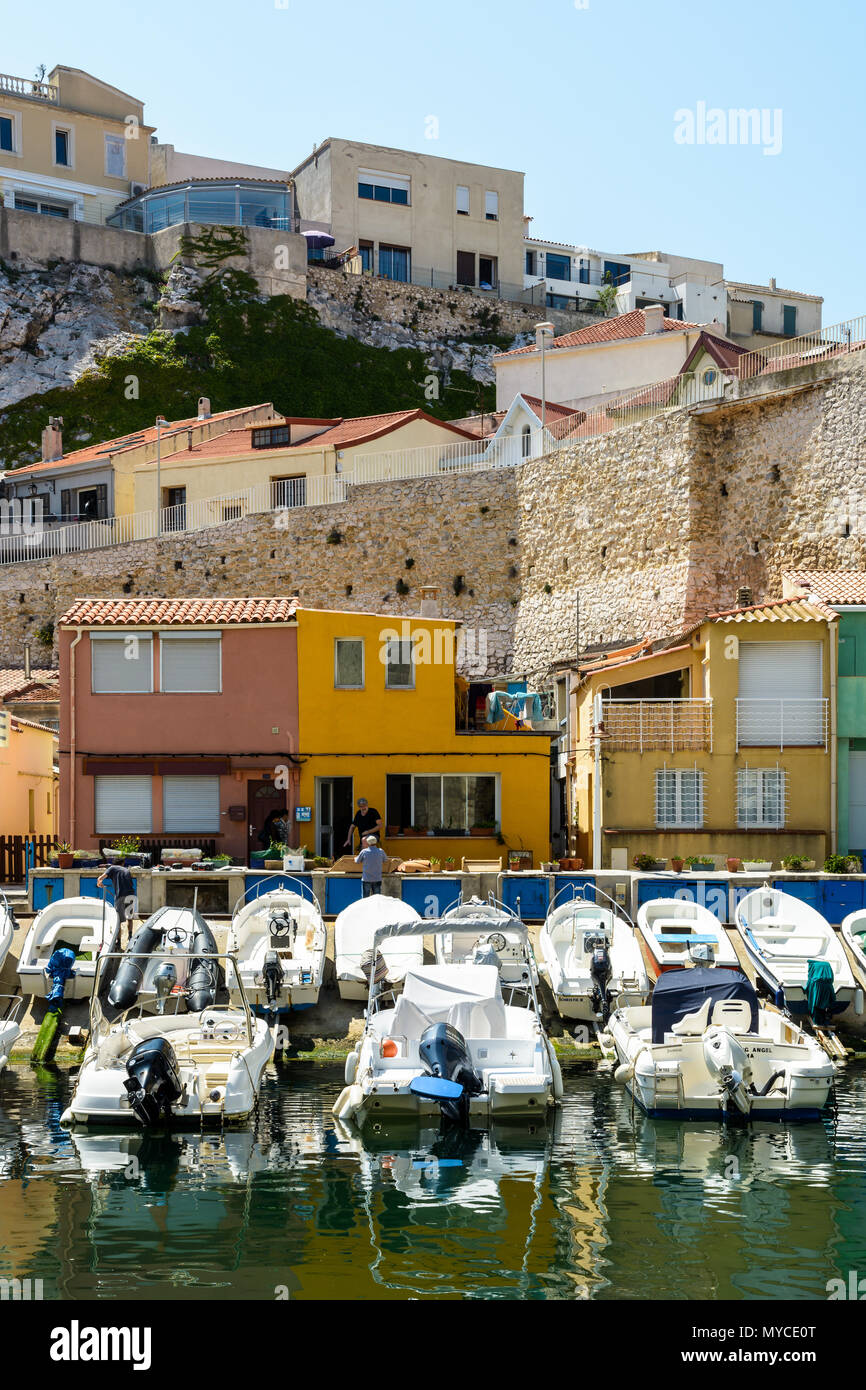 Le petit port du Vallon des Auffes à Marseille par un matin ensoleillé avec des bateaux amarrés devant cabanons colorés et maisons en dessous de la falaise. Banque D'Images