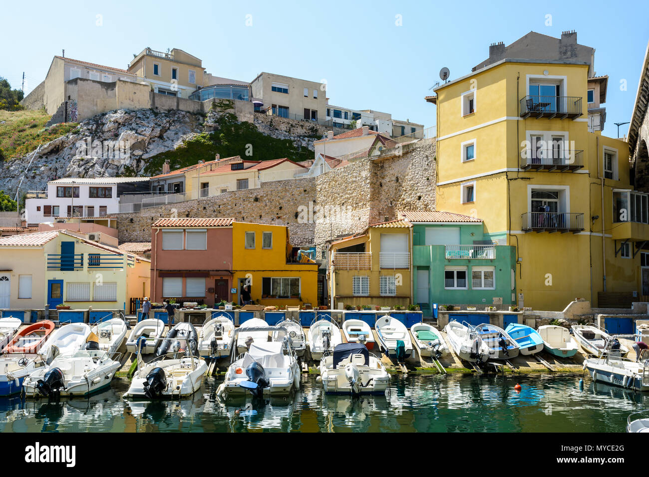 Le petit port du Vallon des Auffes à Marseille par un matin ensoleillé avec des bateaux amarrés devant des maisons colorées au-dessous de la falaise. Banque D'Images