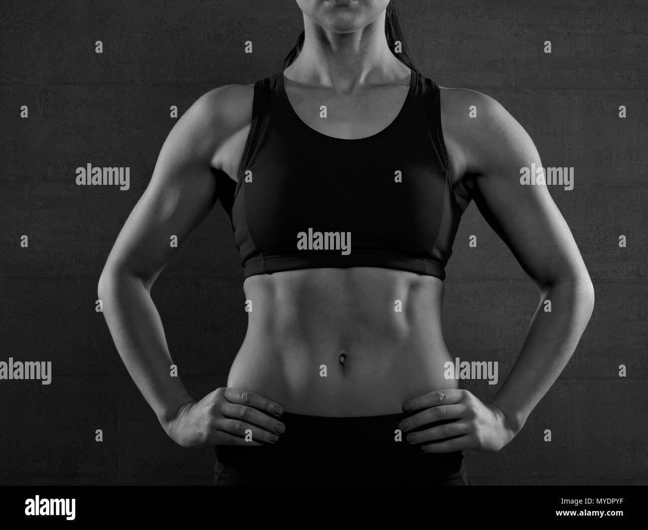 Jeune femme en top sport avec les mains sur les hanches, portrait. Banque D'Images