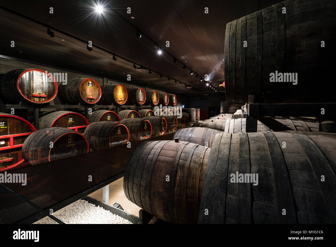 Une rangée de tonneaux de vin et fûts stockés dans un tunnel souterrain à ambiance contrôlée. Banque D'Images