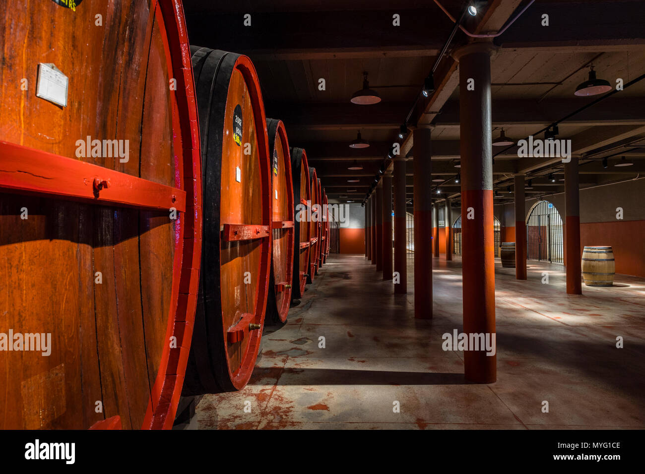 Une rangée de tonneaux de vin et fûts stockés dans un tunnel souterrain à ambiance contrôlée. Banque D'Images