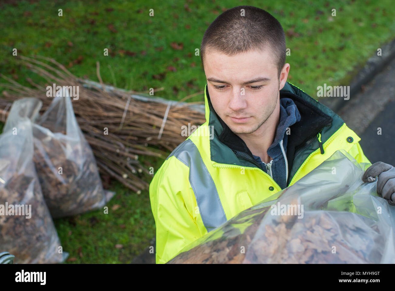 Jeune travailleur avec sac de feuilles mortes Banque D'Images