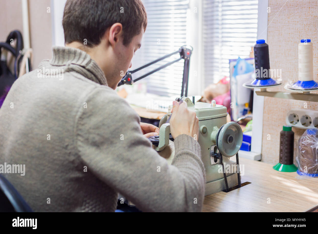 Professionnel hommes skinner, fourreur à l'aide de la machine à coudre spéciale pour coudre la peau de fourrure à l'atelier, atelier. La mode et le travail du cuir concept Banque D'Images