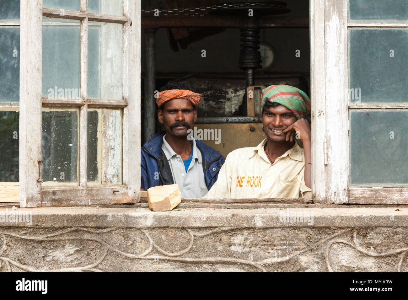 Deux travailleurs en regardant par la fenêtre à l'Kolukkumalai, usine de thé de Munnar, Kerala, Inde. Banque D'Images