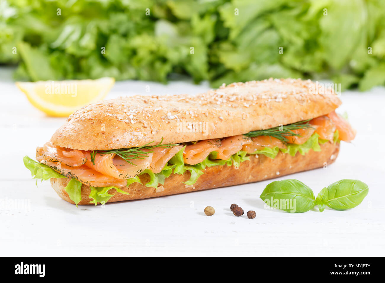 Sandwich baguette sous les grains entiers avec du poisson Saumon fumé sur planche de bois bois Banque D'Images