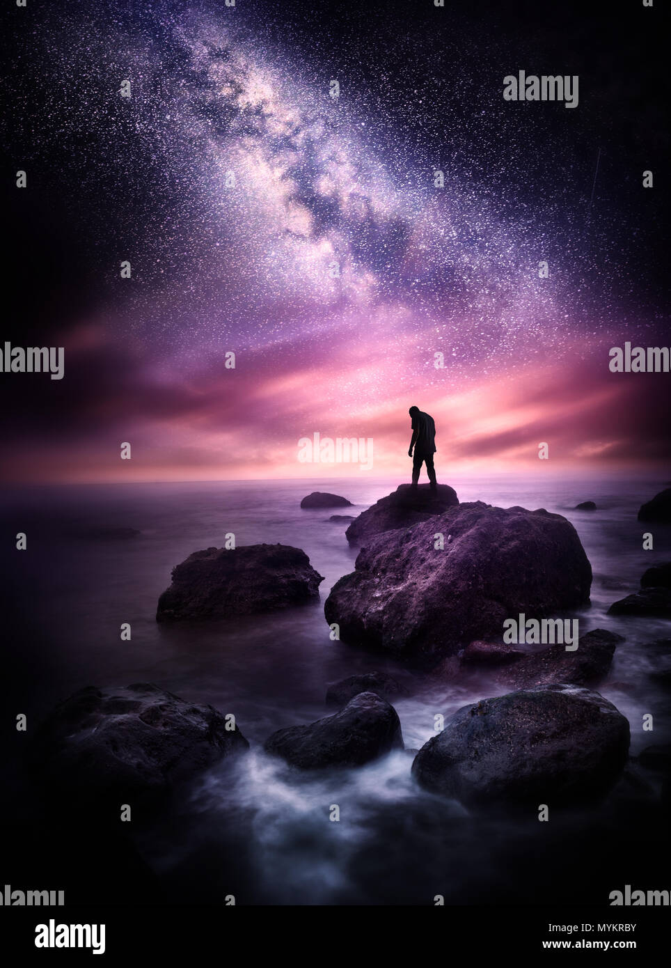 Paysage de la mer de nuit avec la Voie lactée. Un homme se tient sur une ligne de rivage rocheux avec les étoiles au-dessus de lui. Photo composite. Banque D'Images