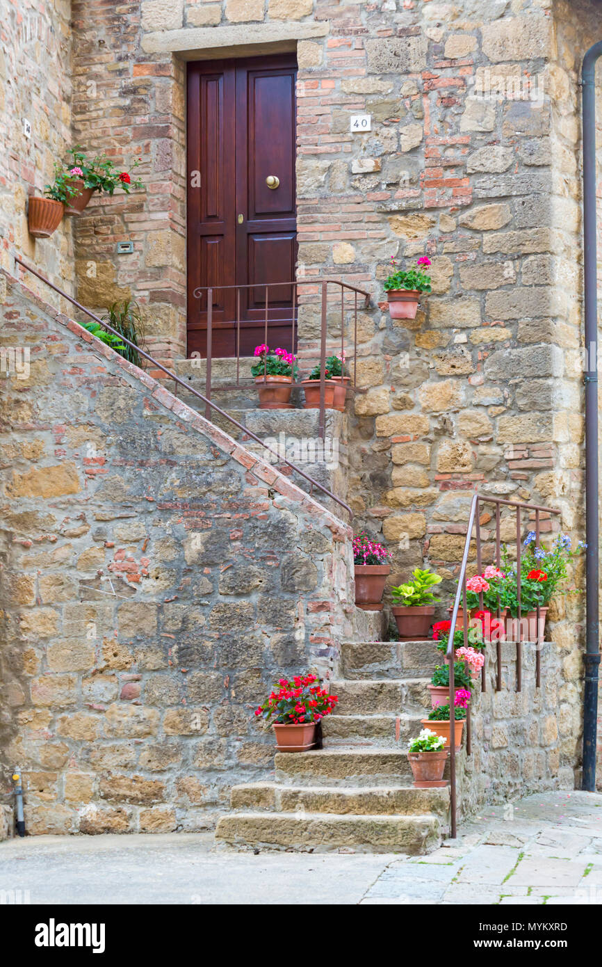 Des pots de fleurs colorées à l'extérieur de l'escalier en pierre dans village médiéval ville de Monticchiello, près de Pienza, Toscane, Italie en mai Banque D'Images