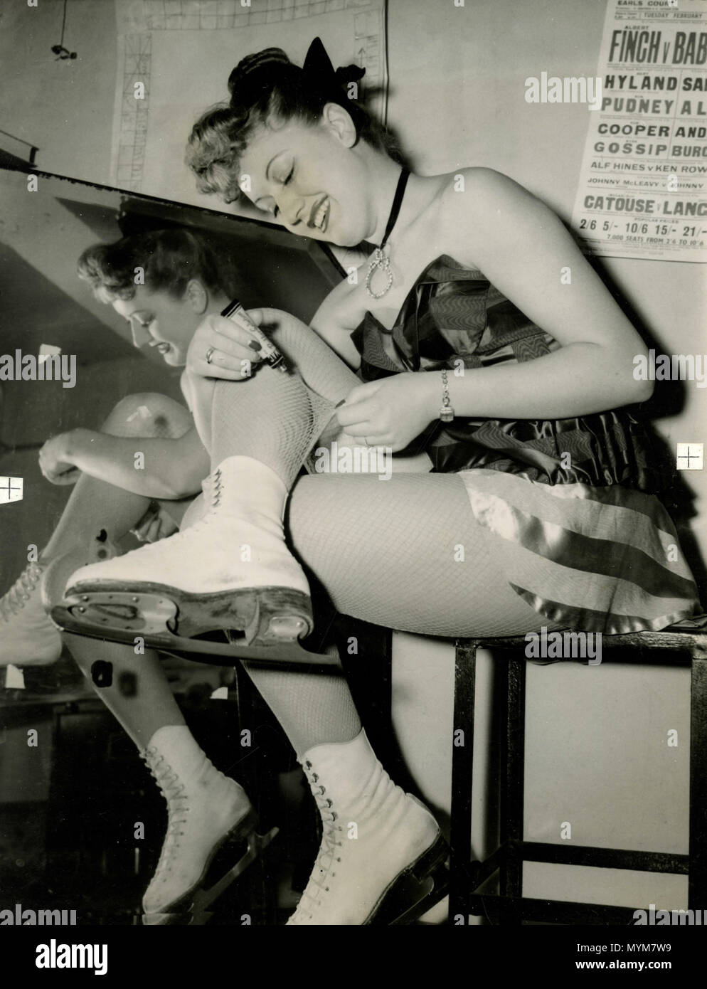 Fille avec le patineur de roller la réparation de ses bas, 1950 Banque D'Images