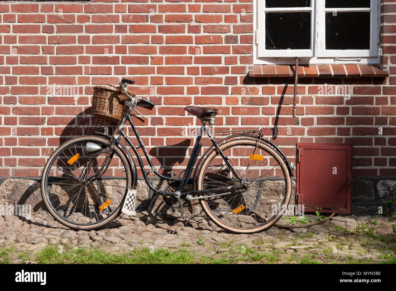 Vélo Vintage appuyée sur un mur de brique d'une maison Banque D'Images