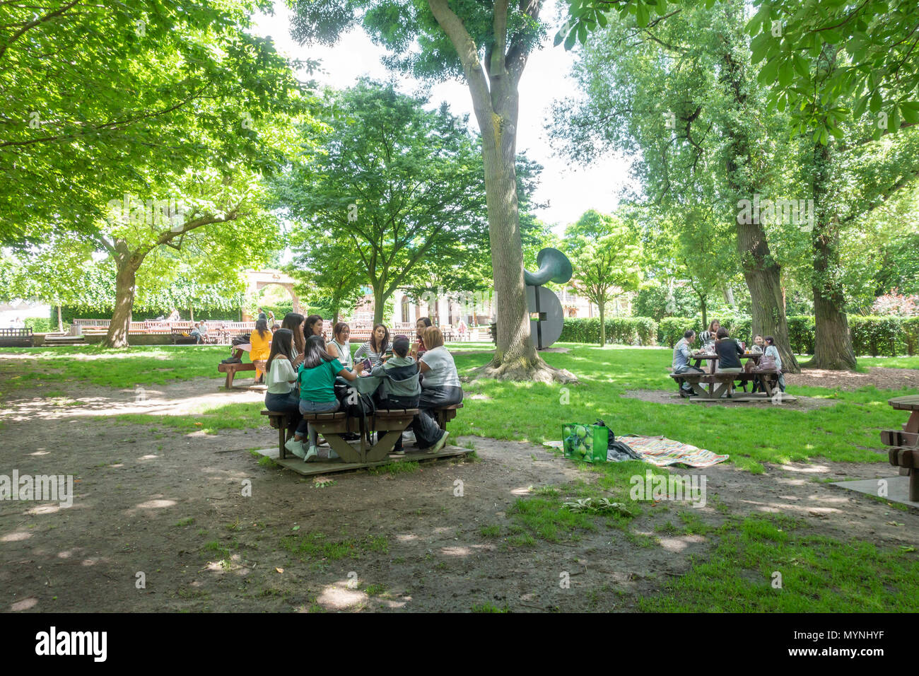 Les amis de s'asseoir ensemble à des tables de pique-nique dans la région de Holland Park, Londres. Banque D'Images