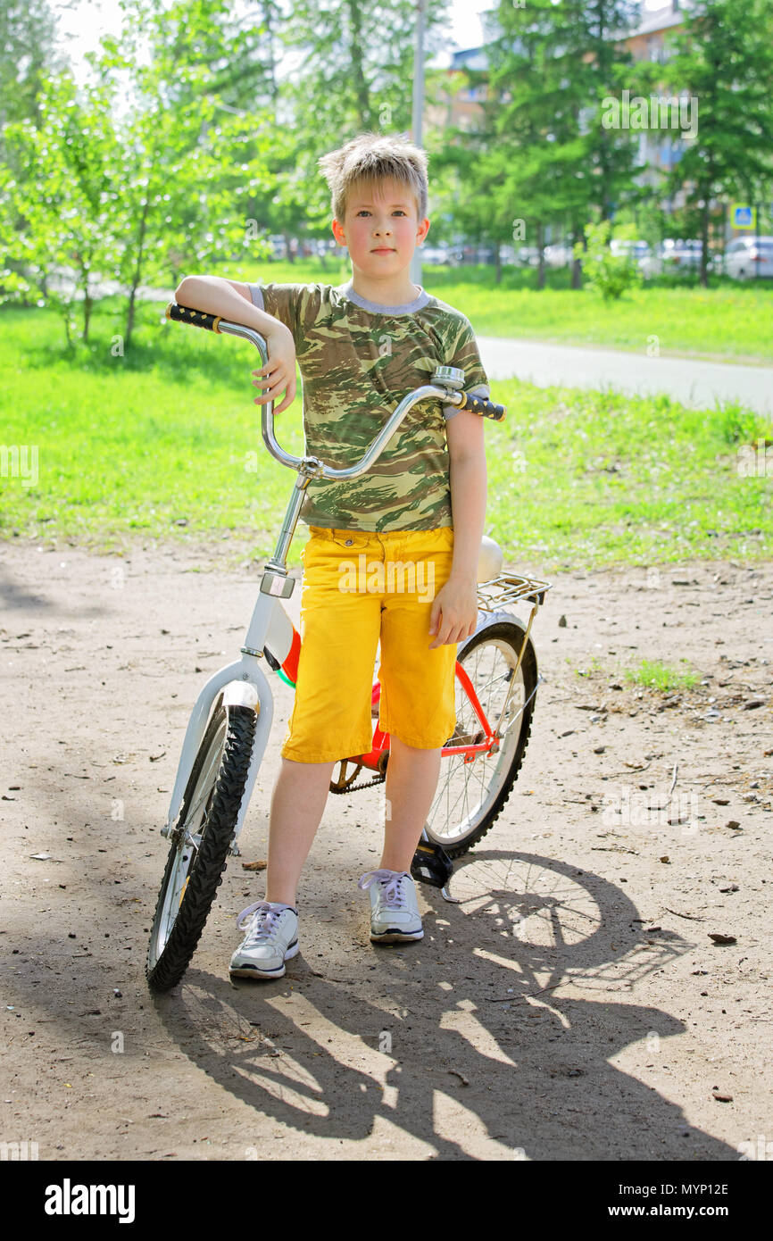 Un adolescent garçon posant près de son vélo dans un parc d'été. Joie de repos actif pendant les vacances Banque D'Images