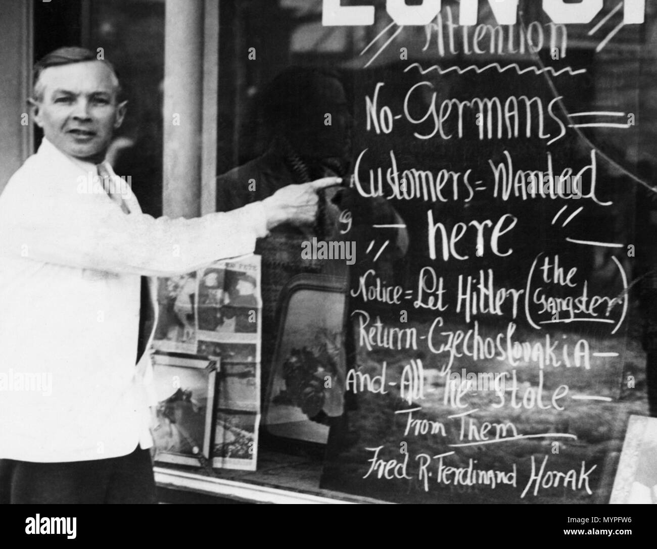 . Anglais : opérateur Restaurant Fred Horak de Somerville, Massachusetts, mettre ce signe sur la fenêtre de sa salle à manger, 18 mars 1939 illustré. Horak fut originaire de Prague, Tchécoslovaquie. (Photo AP) 中文(繁體）‎ 美聯社 麻薩諸塞州薩默維爾市一家餐廳老闆弗雷德 :：霍拉克指著窗外的門口招牌 拍攝於。·1939年3月18日，霍拉克是生於捷克斯洛伐克的布拉格。： 招牌標語 本店不歡迎德國人，"""那個匪徒 把捷克斯洛伐克和他巧取豪奪的國家全部還來 希特勒（）！ »‎（简体 中文）：马萨诸塞州索莫尔维勒市的餐馆经营者弗雷迪 美联社 : 霍拉克在餐厅的橱窗里放出一块标语牌 摄於。·1939年3月18日。。 霍拉克来自于捷克斯洛伐克的布拉格 标语牌： 这里不接待德国人。»«（那歹徒 希特勒 »）从捷克斯拉伐克及所有他窃取的国家滚回去。"[1]：マサチューセッツ州サマービル AP通信の写真 日本語 :、チェコスロバキア人レストランの店長フレッド．ホラーク。 . 18 mars 1939. Associated Press. Restaurant 452 Fred opérateur Horak de Somerville, 19 Banque D'Images