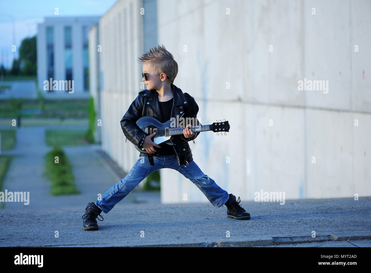 Un petit garçon mignon, guitariste de blouson de cuir et lunettes de jouer de la guitare. L'idole des jeunes. L'intérêt de l'enfant et passe-temps. Être comme une rock star. Banque D'Images