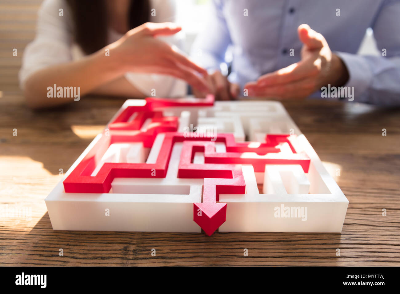 Close-up of Puzzle labyrinthe avec flèche rouge en face des gens d'affaires Banque D'Images