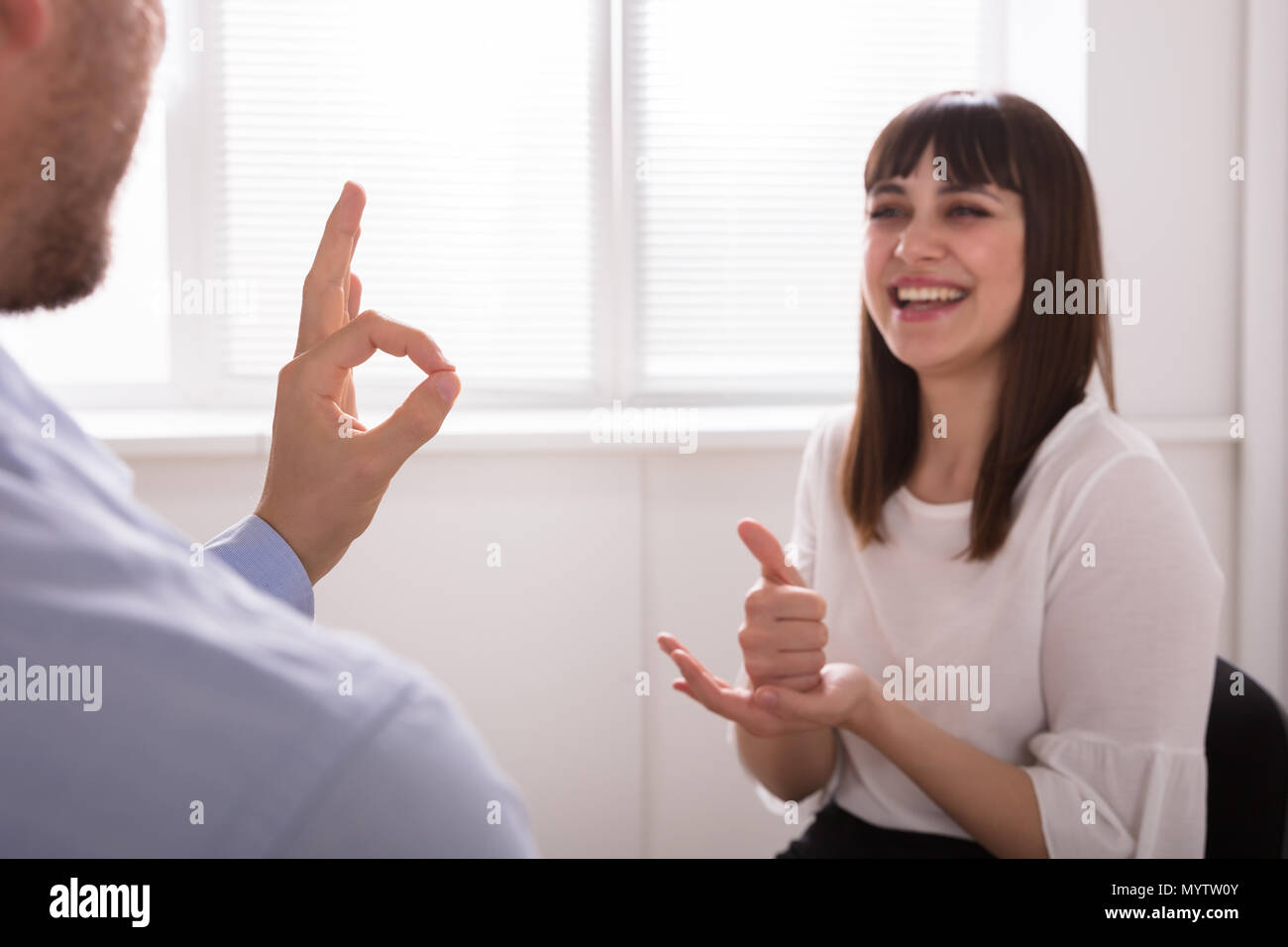 Souriante jeune femme et l'homme parle avec la langue des signes sur fond blanc Banque D'Images