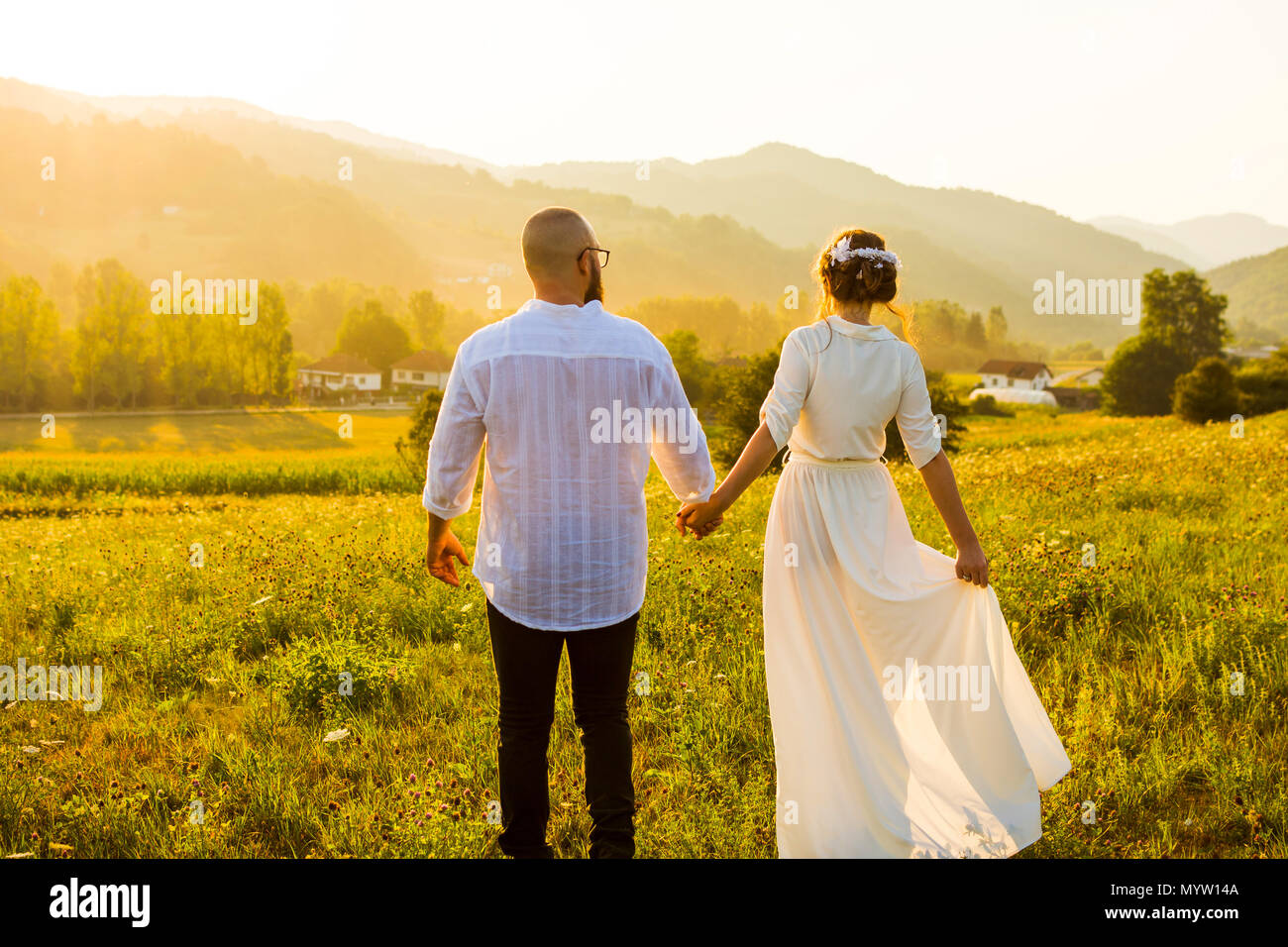 Couple en train de marcher sur le terrain avec vue sur le coucher de soleil romantique Banque D'Images