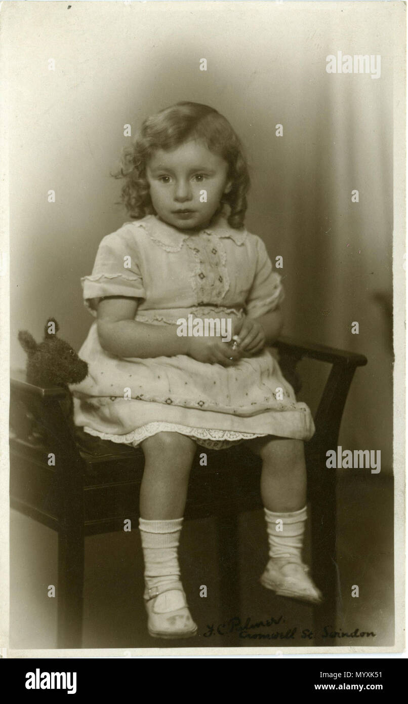 . Photo Portrait d'un enfant assis à Swindon, Wiltshire, Angleterre en 1920 ou 1930. Le photographe a Fred C. Palmer de Tower Studio, Herne Bay, Kent ca.1905-1920, et de 6 Cromwell Street, Swindon ca.1920-1936. Il est mortes 1936-1939. Points d'intérêt l'enfant est assis sur un tabouret de piano. La robe est brodé à la main mais n'est pas nouveau, et l'ourlet a été organisée pour montrer le nouveau jupon. L'enfant a été ringleted pour la photographie, et ses lèvres sont éventuellement rouged pour la même raison, mais ses chaussures révèlent beaucoup d'activités de plein air. Elle a été donnée un metal obj Banque D'Images