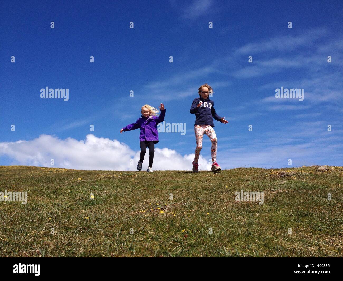 Les soeurs s'amusant en marche en bas de la colline sur le Great Orme à Llandudno dans le Nord du Pays de Galles sur un week-end venteux mais ensoleillé. Banque D'Images Les soeurs s'amusant en marche en bas de la colline sur le Great Orme à Llandudno dans le Nord du Pays de Galles sur un week-end venteux mais ensoleillé. Banque D'Images