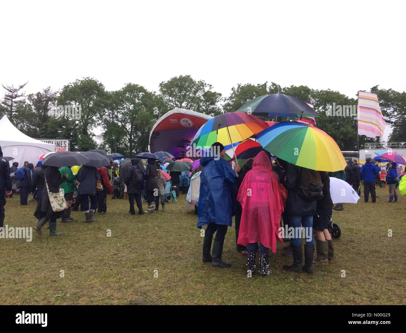 Les gens portent parasols colorés à un festival Womad des pluies dans Charlton Park, Wiltshire, Royaume-Uni Banque D'Images