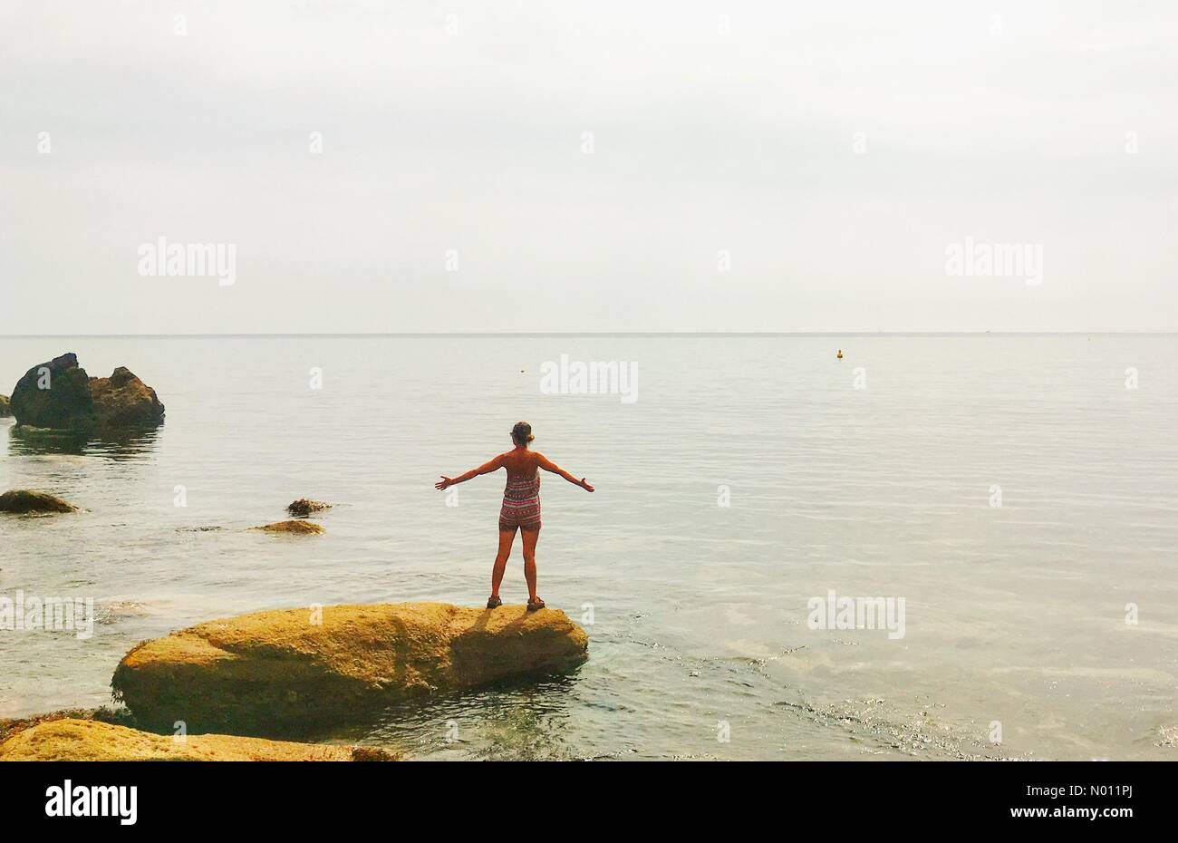 Watcombe beach, Devon, UK. 17 juillet, 2019. Météo France : journée chaude Watcombe beach. Raich Keene se dresse sur un rocher surplombant la mer calme. /StockimoNews nidpor : Crédit/Alamy Live News Banque D'Images