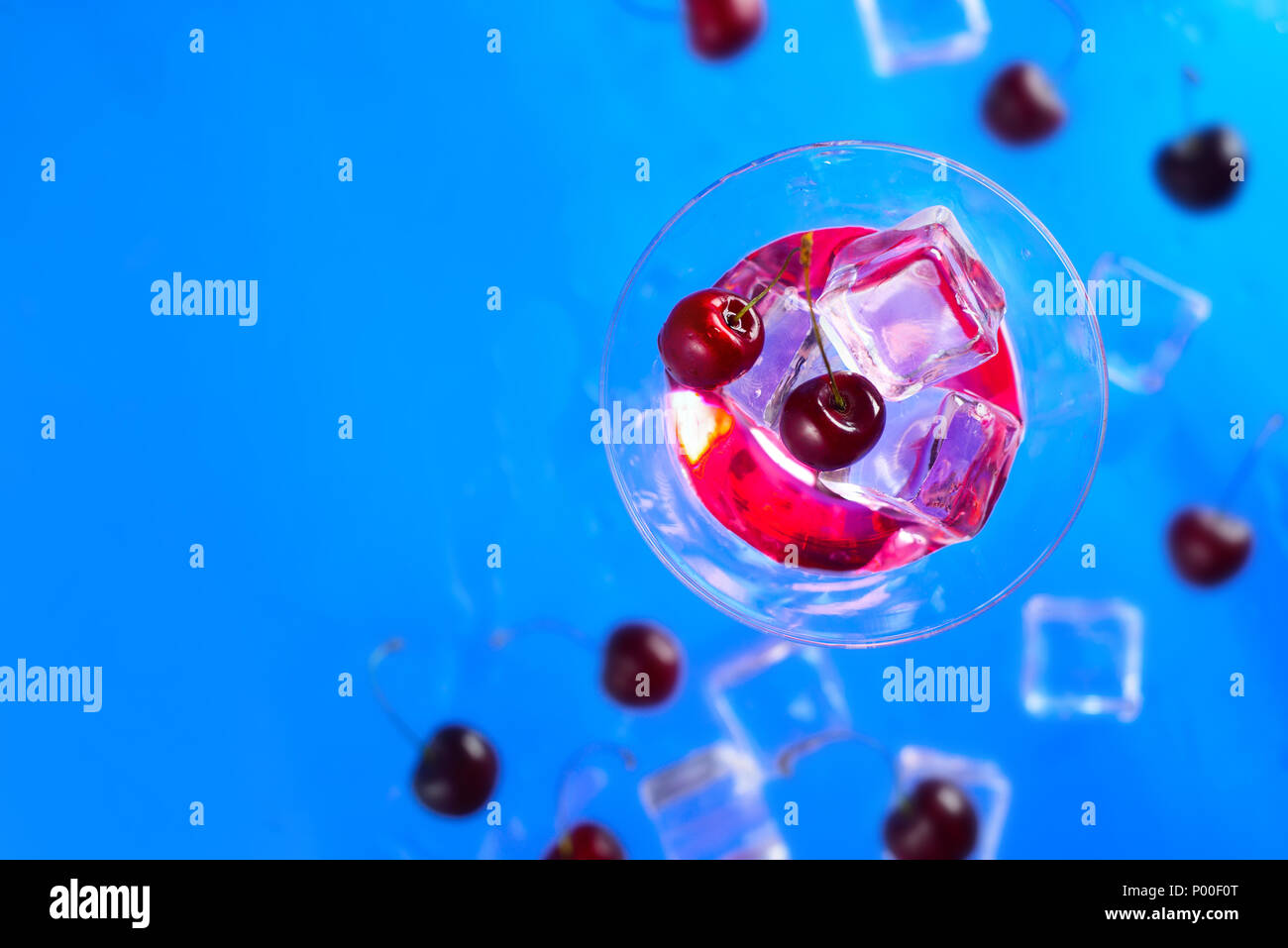 Verre à cocktail liqueur de cerise à partir de ci-dessus, sur un fond bleu. Boisson fraîche mise à plat avec copie espace Banque D'Images