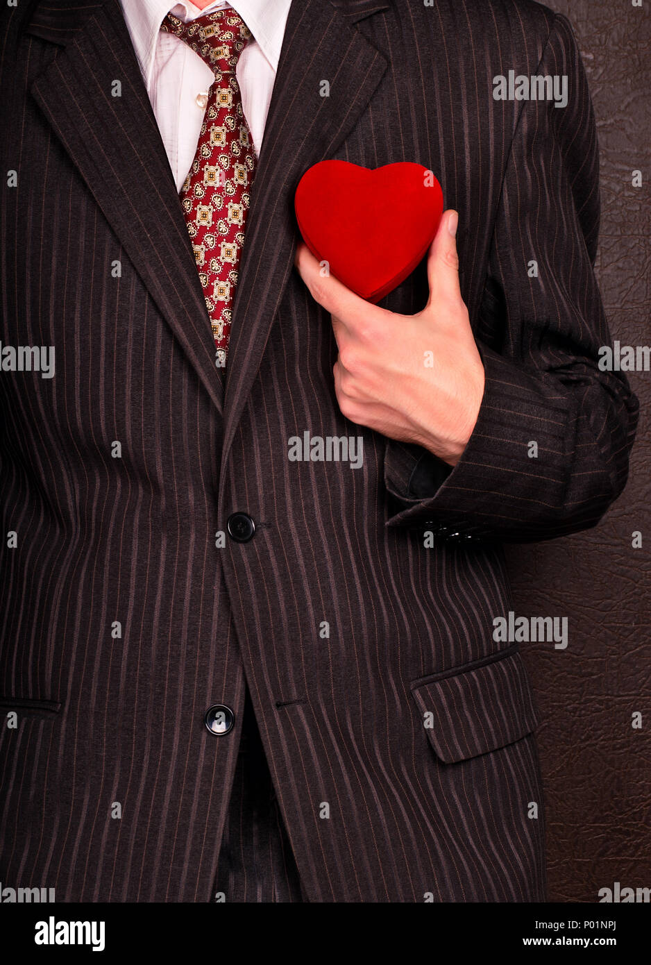 Homme d'affaires en costume sombre tenant un cœur symbolisant Valentines Day Banque D'Images