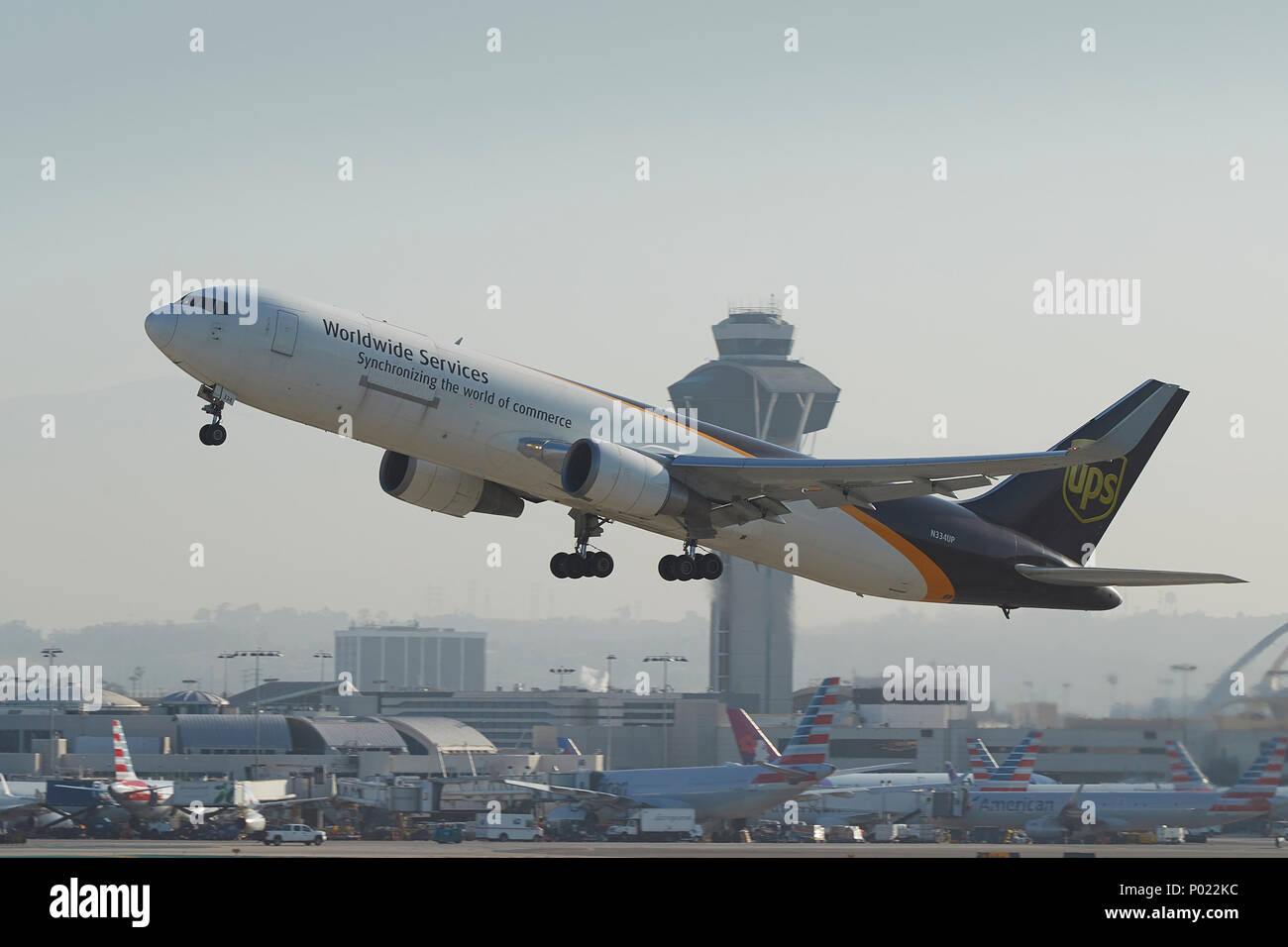 UPS, Worldwide Services, Boeing 767-300F cargo, décollant de l'Aéroport International de Los Angeles, LAX. La tour de contrôle de l'ATC derrière. Banque D'Images