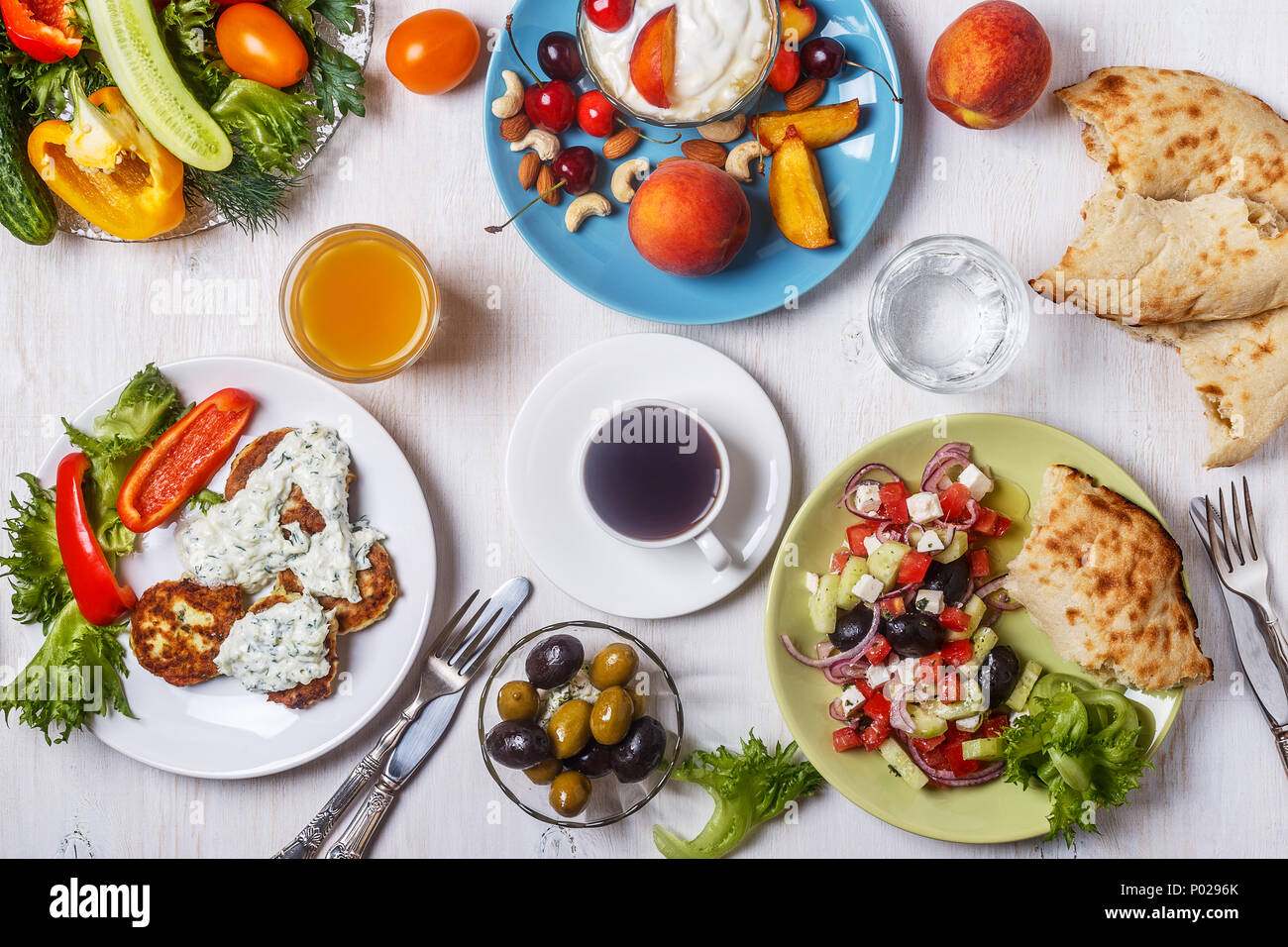 Apéritifs grecs - beignets de courgette avec sauce tzatziki, salade grecque, yaourt aux fruits et noix, olives, légumes et fines herbes, vue d'en haut. Banque D'Images