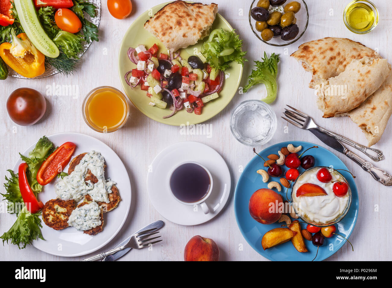 Apéritifs grecs - beignets de courgette avec sauce tzatziki, salade grecque, yaourt aux fruits et noix, olives, légumes et fines herbes, vue d'en haut. Banque D'Images