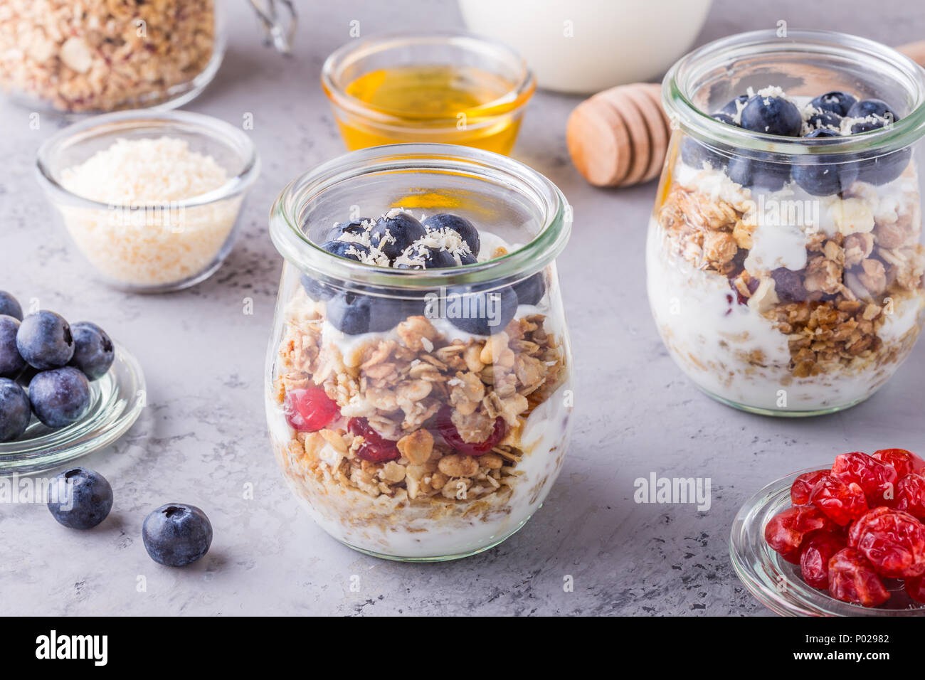 Petit-déjeuner sain - pots de verre de flocons d'avoine avec des fruits frais, du yaourt et du miel, selective focus. Banque D'Images