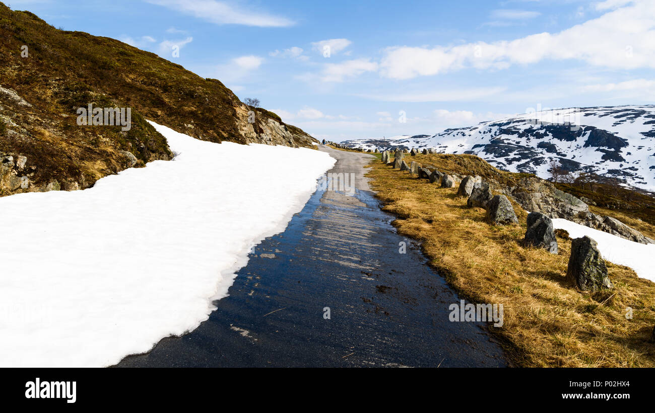 Petit et étroit chemin de campagne dans les montagnes. La neige et la glace est en train de fondre au soleil. Situé au-dessus du lac Kjelavatn in Telemark, Norvège. Banque D'Images