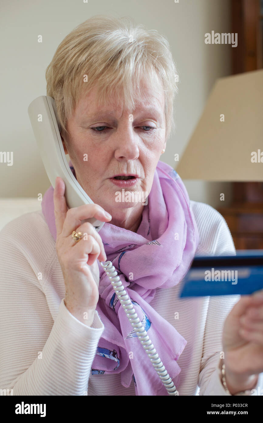Senior Woman en donnant des détails de carte de crédit au téléphone Banque D'Images