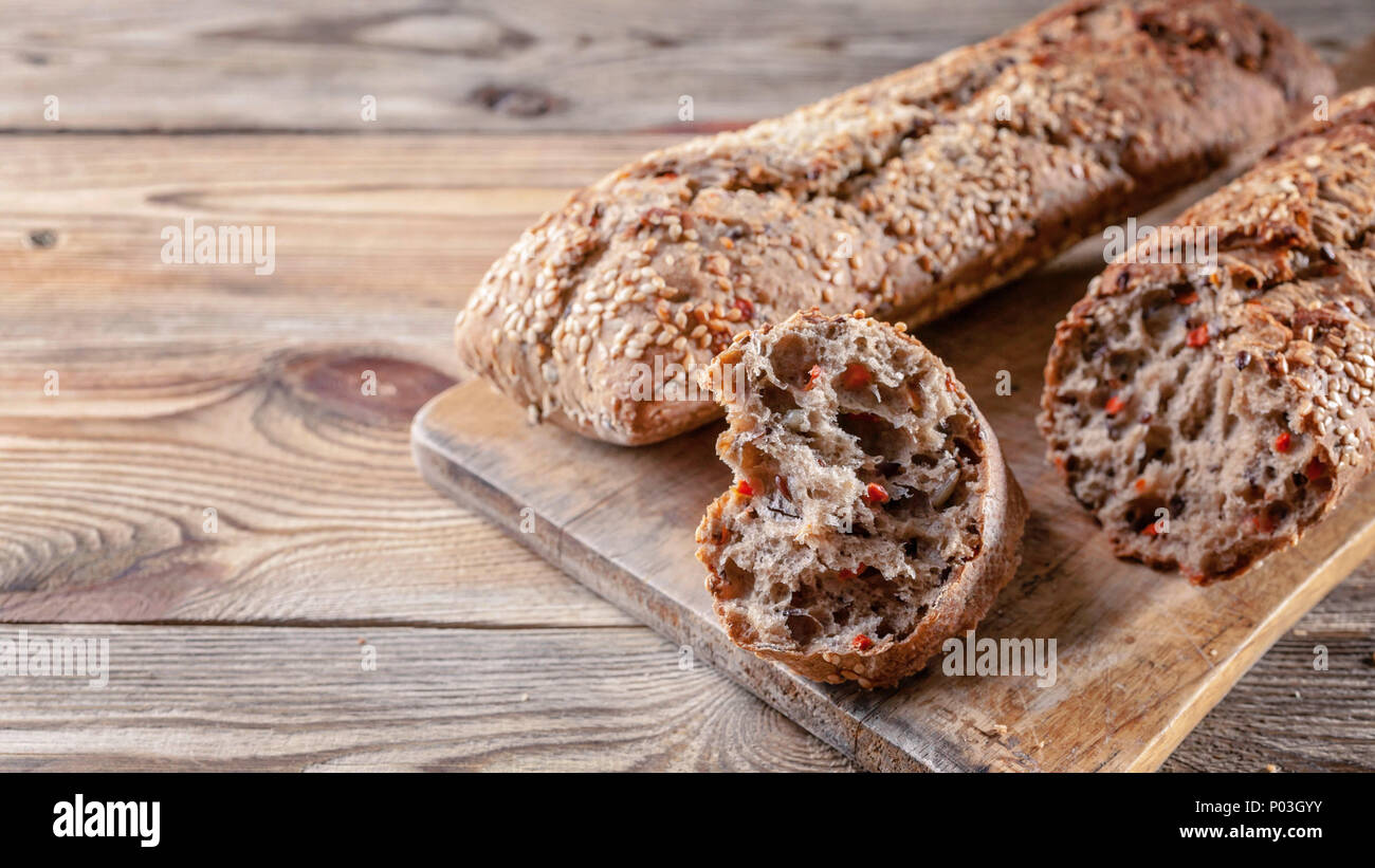 Baguettes à l'appétissant avec des graines de sésame et de noix sur une planche à découper sur un fond de bois. Concept d'aliments sains Banque D'Images