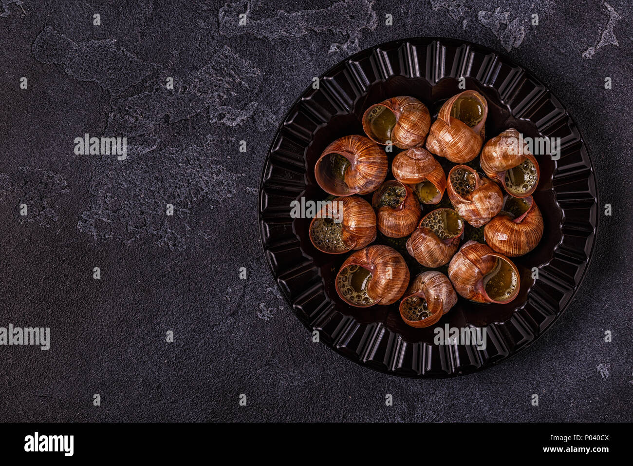 Les escargots frits avec du citron, de la baguette et le persil, vue du dessus. Banque D'Images