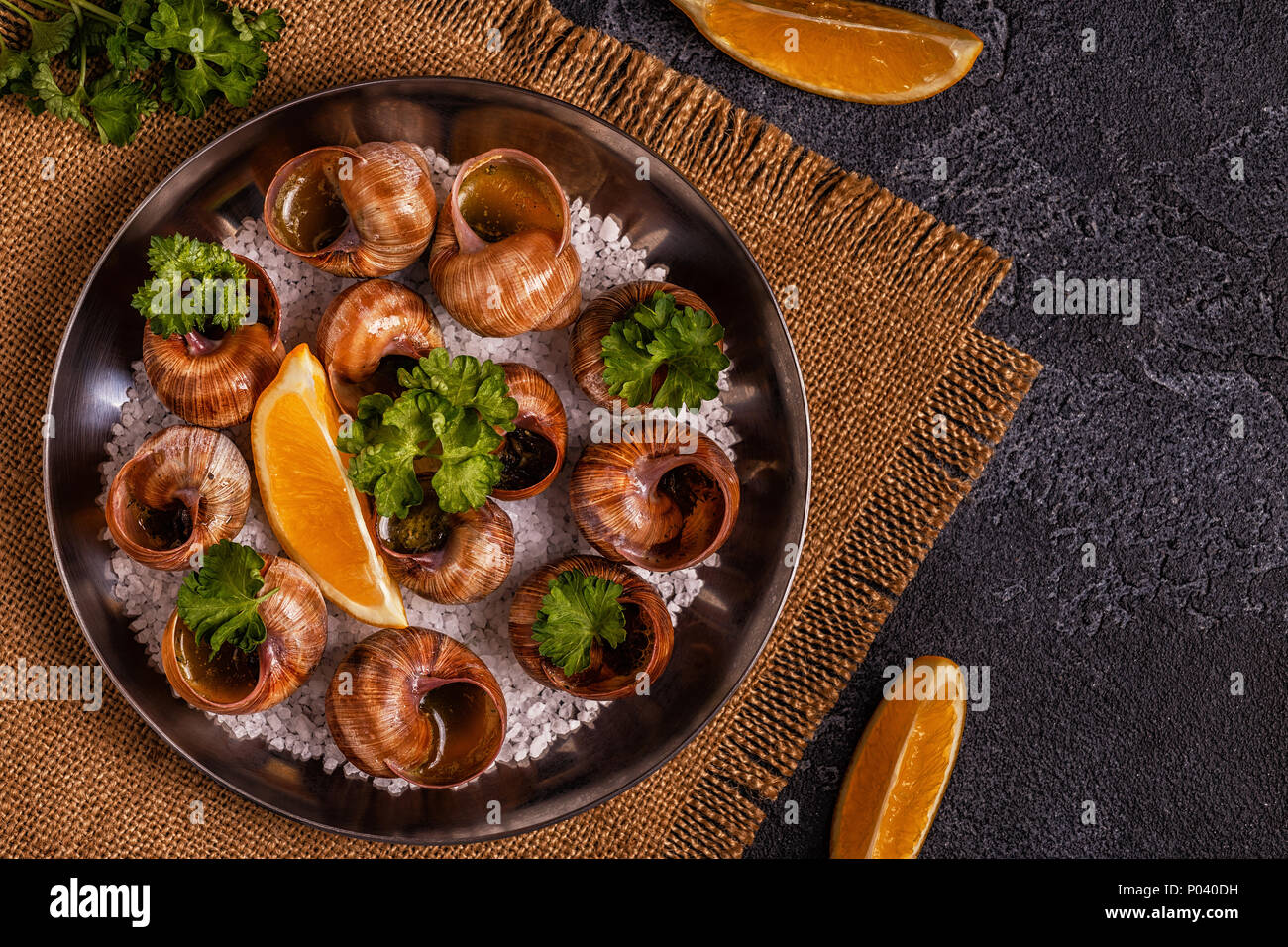 Les escargots frits avec du citron, de la baguette et le persil, vue du dessus. Banque D'Images