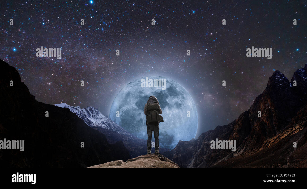 Sac à dos avec un homme debout sur le sommet de la montagne de nuit, et silhouette avec des montagnes pleine lune et ciel plein d'étoiles Banque D'Images