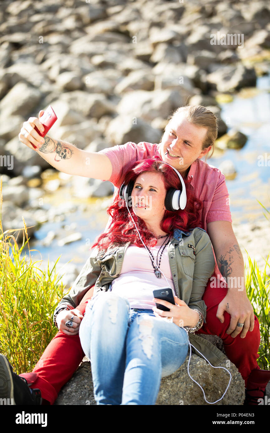 Jeune couple amoureux avec des Tatouages et piercings profitant du temps ensemble dans la nature au bord de la rivière Banque D'Images