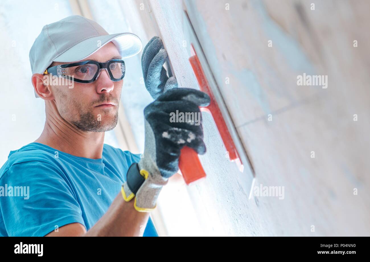 Dernière mise à niveau avant que la peinture des murs. Young Construction Worker Nettoyage du mur. Banque D'Images